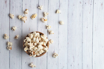 Salt popcorn on the wooden table. Popcorn in a wooden bowl.