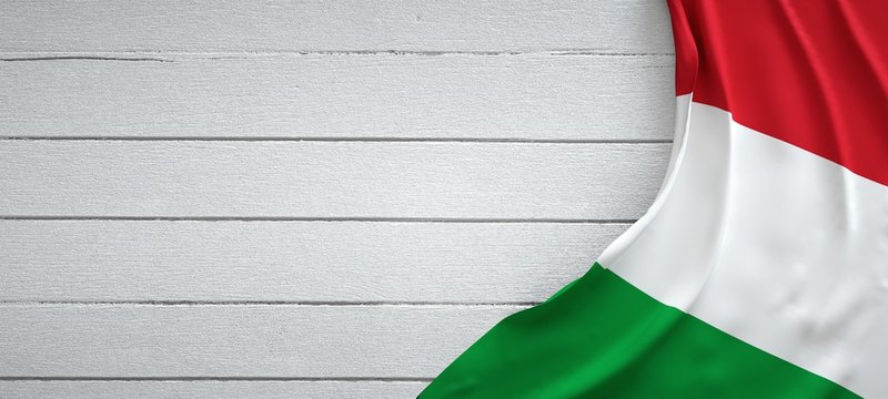 Italian flag, on top of white wood. Wrinkled fabric.