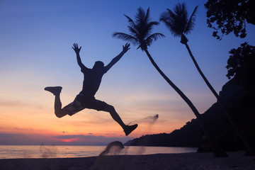 Asian man jumping fun on the beach at sunrise