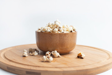 Salt popcorn on the wooden table. Popcorn in a wooden bowl.