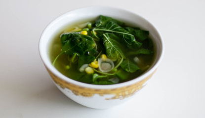 Sayur Bening Bayam or Spinach Clear Soup on white background. Boiled spinach with corn. Indonesian food.