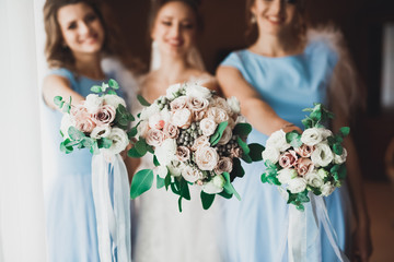 Bride with bridesmaids holding luxury wedding bouquet of different flowers on the wedding day