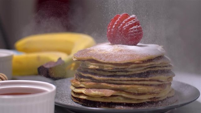 Sprinkling of American pancakes with powdered sugar. Slow Motion