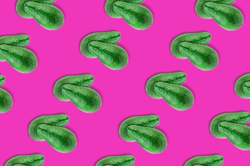 Diagonal rows of green whole fresh raw avocados on pink background