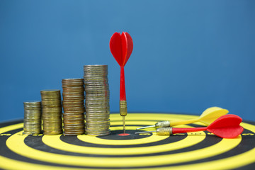 Red dart arrow hit the center target of dartboard and money coin metaphor marketing or saving money...