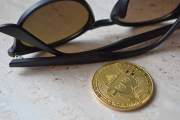 Cryptocurrency coin on sunglasses background