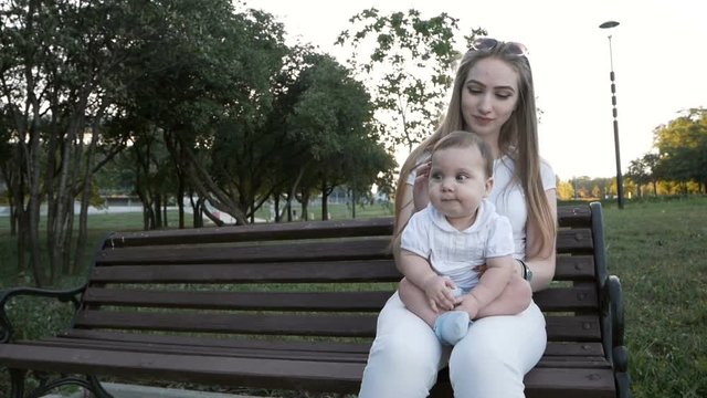 Slow motion of mother and daughter sitting on the bench in park