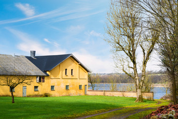 Yellow farm house by a lake in the spring