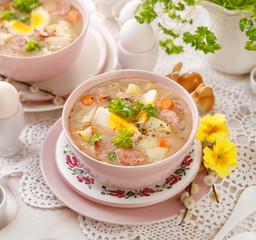 The sour soup (Żurek), polish Easter soup with the addition of sausage, hard boiled egg and vegetables in a ceramic bowl. Traditional Easter food in Poland