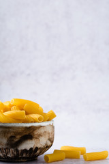 tortiglioni ungekocht roh in einer schuessel vor grauem hintergrund mit viel freiraum fuer text...