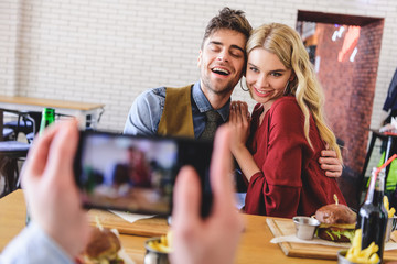 selective focus of beautiful and hugging couple posing for photo at cafe