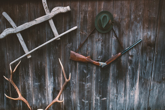 Professional Hunters Equipment For Hunting. Rifle, Deer, Roe Deer Trophy Sculs And Others On A Wooden Black Background. Trophy Sculs From Roe Deer And Deer On The Wall.