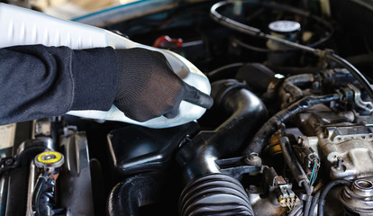 Fototapeta premium The mechanic is filling the engine oil.Auto mechanic Preparing For the work.car maintenance