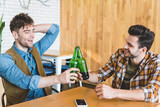 handsome and smiling friends cheering with glass bottles of beer