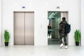 Teenager boy with casual clothes and white sneakers enters in elevator.