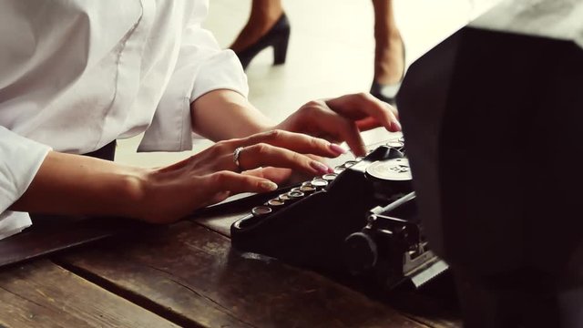 Beautiful girl is typing on an old typewriter. Loft atmosphere in vintage style.
