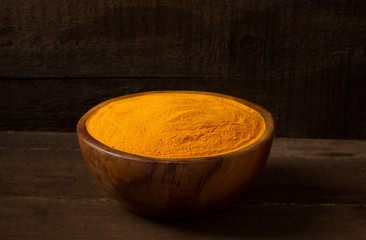 Turmeric curcuma in wooden bowl and wooden background