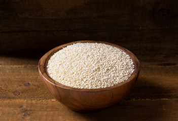 Sesame seeds in wooden bowl on wooden background