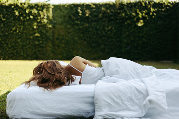 Girl sleeping on matress on grass