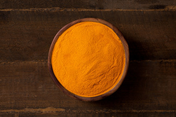 Turmeric curcuma in wooden bowl and wooden background