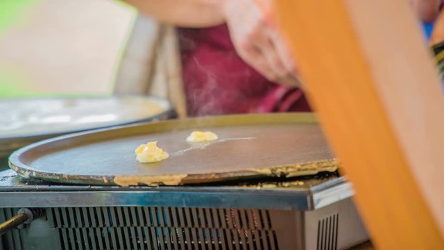 A chef is putting butter on the shelf and the butter starts melting. When the butter melts, the chef will start making crepes for the people at the straw hat festival.