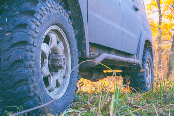 Fototapeta na wymiar Wheels off-road car standing on the grass in the forest