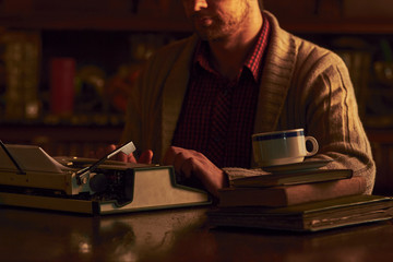 Young man writing on old typewriter.