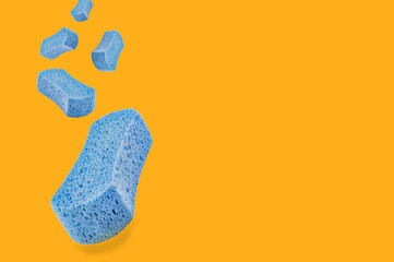 Falling porous blue sponges on yellow background with copy space for your text