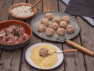 Meatballs ready for frying and products for their manufacture on ceramic plates, shot close-up.