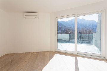 Empty room with white walls and windows overlooking the mountains
