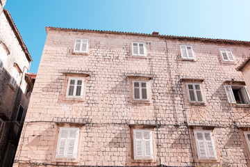 Fototapeta na wymiar The old town of Trogir on sunny summer day. White brick wall with windows. Architecture of Trogir old town