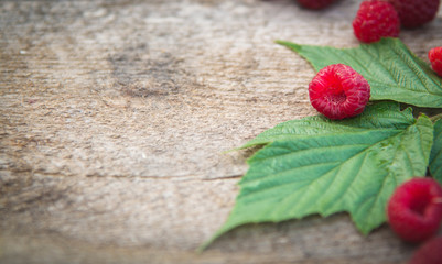 a scattering of raspberry and raspberry leaves on a wooden background