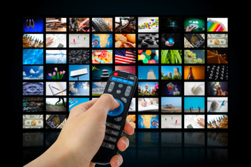 TV screen with lot of pictures and hands of man with remote control .