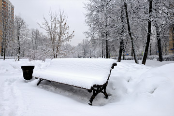 Bench in a park filled up with a snow