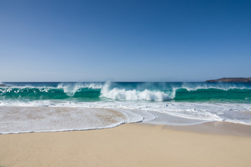 white sand of a beautiful beach and  waves of a turquoise sea under a blue sky