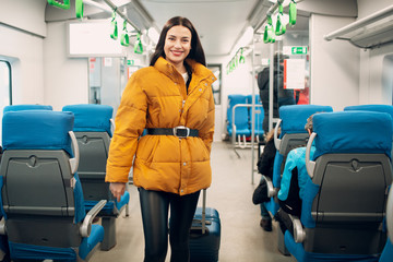 Young female walking with luggage and finding her seat in railway train.