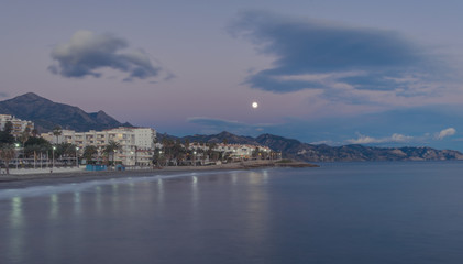 Fototapeta na wymiar Nerja, Malaga, Andalusi, Spain - January 20, 2019: Moon at the beginning of the night over the coastal town of Nerja, southern Spain