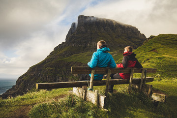 bro Guys chilling on bench at Gasadalur sunset amazing view point over the ocean with cliffs...