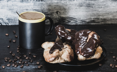 Coffee and chocolate eclairs on a wooden background