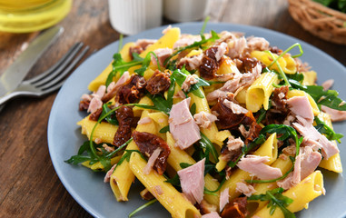 Penne pasta with tuna chunks, rucola and dry tomatoes