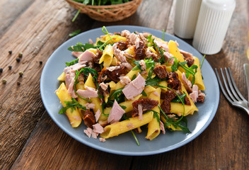 Penne pasta with tuna chunks, rucola and dry tomatoes