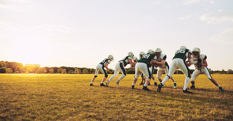 American football players doing practicing defense on a sports f