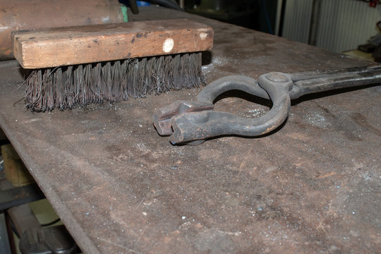 Tools sit on a metal table in the blacksmith shop with bokeh background. - Powered by Adobe