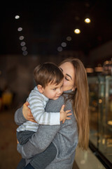 happy family, blonde mother and her beautiful and charismatic little son, the boy is having fun day in a cozy cafe. selective focus, noise effect