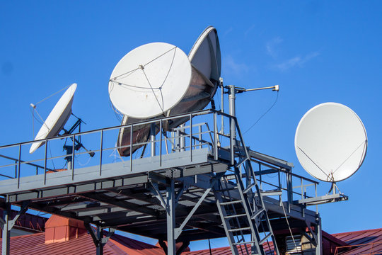 Satellite dishes on the roof of the building, blue sky, parabolic antenna