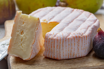 Round piece of French cheese Fleur Rouge made from cow milk served as dessert with fresh figs and pears