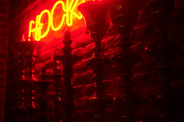 Fototapeta na wymiar line of hookas at red light background. neon hookah sighnboard