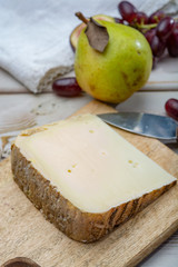 Piece of French cheese Tomme de Brebis made from sheep milk served as dessert with fresh figs and pears