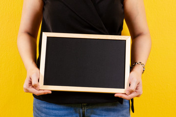 Asian girl in the black cloth holding a wooden black board close up.