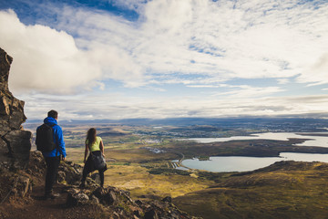 Boy in blue jacket with a girl hiking the Esja mountain near Reykjavik Iceland on a sunny afternoon - obrazy, fototapety, plakaty